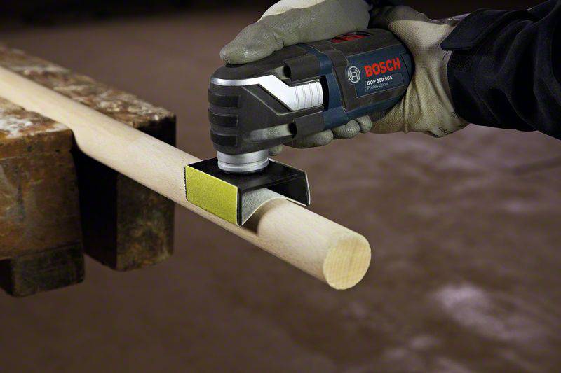 'Una persona usa una levigatrice manuale su un bastone di legno in officina.'