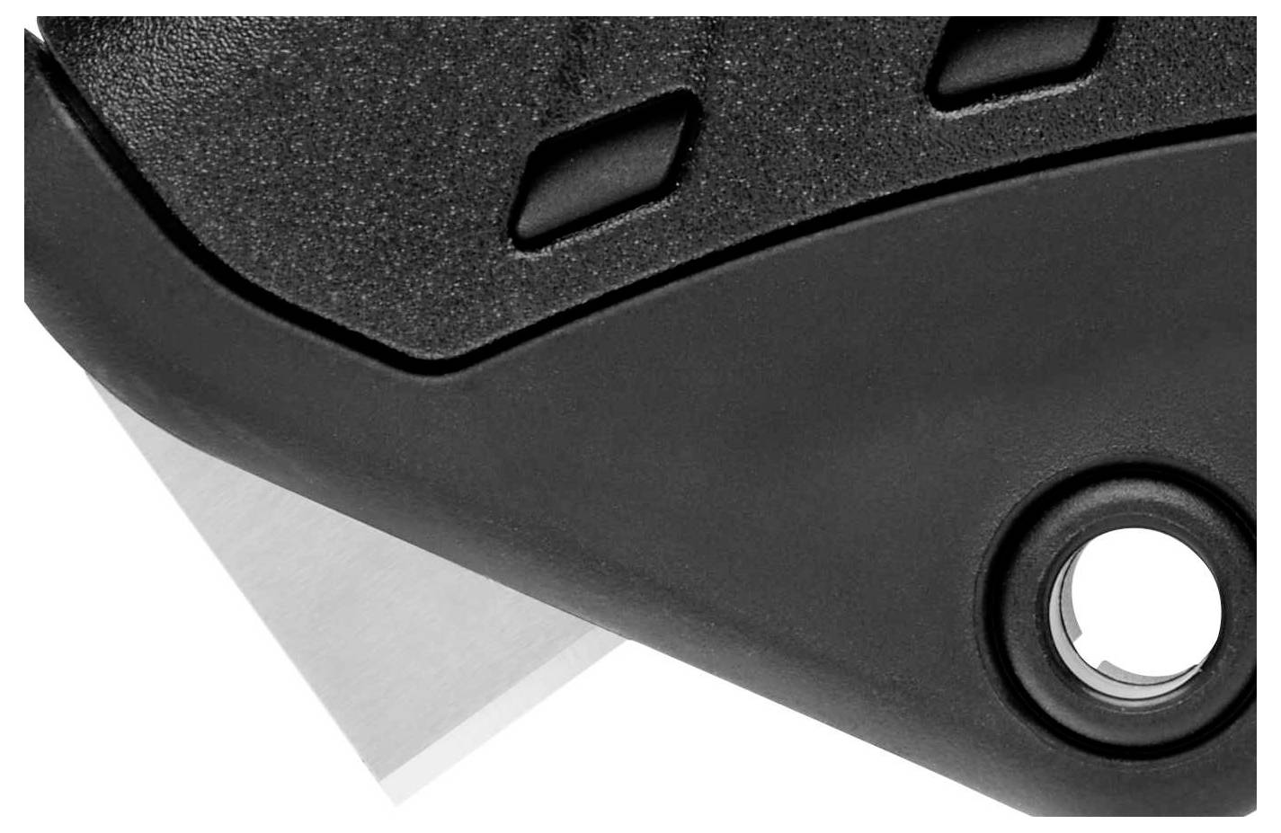 Uno strumento nero con un bordo visibile e dettagli arrotondati. In primo piano è visibile una lama argentata.