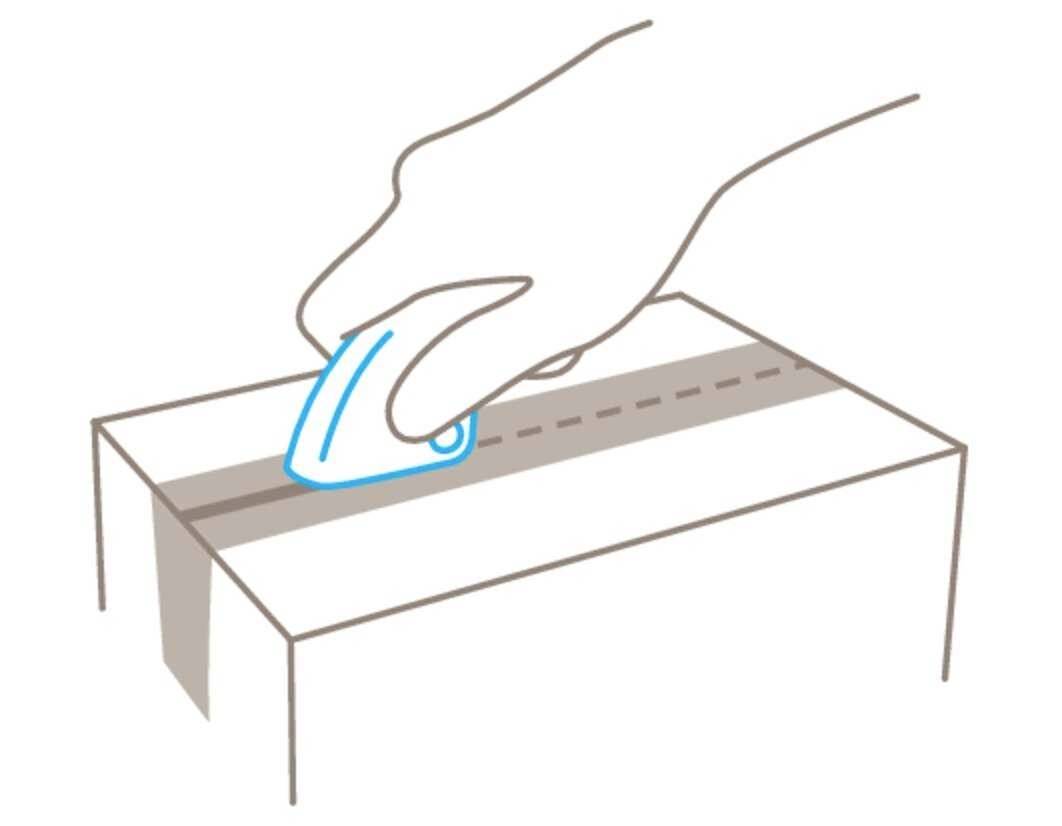 Una mano tiene un coltello e taglia una scatola di cartone lungo una linea tracciata.