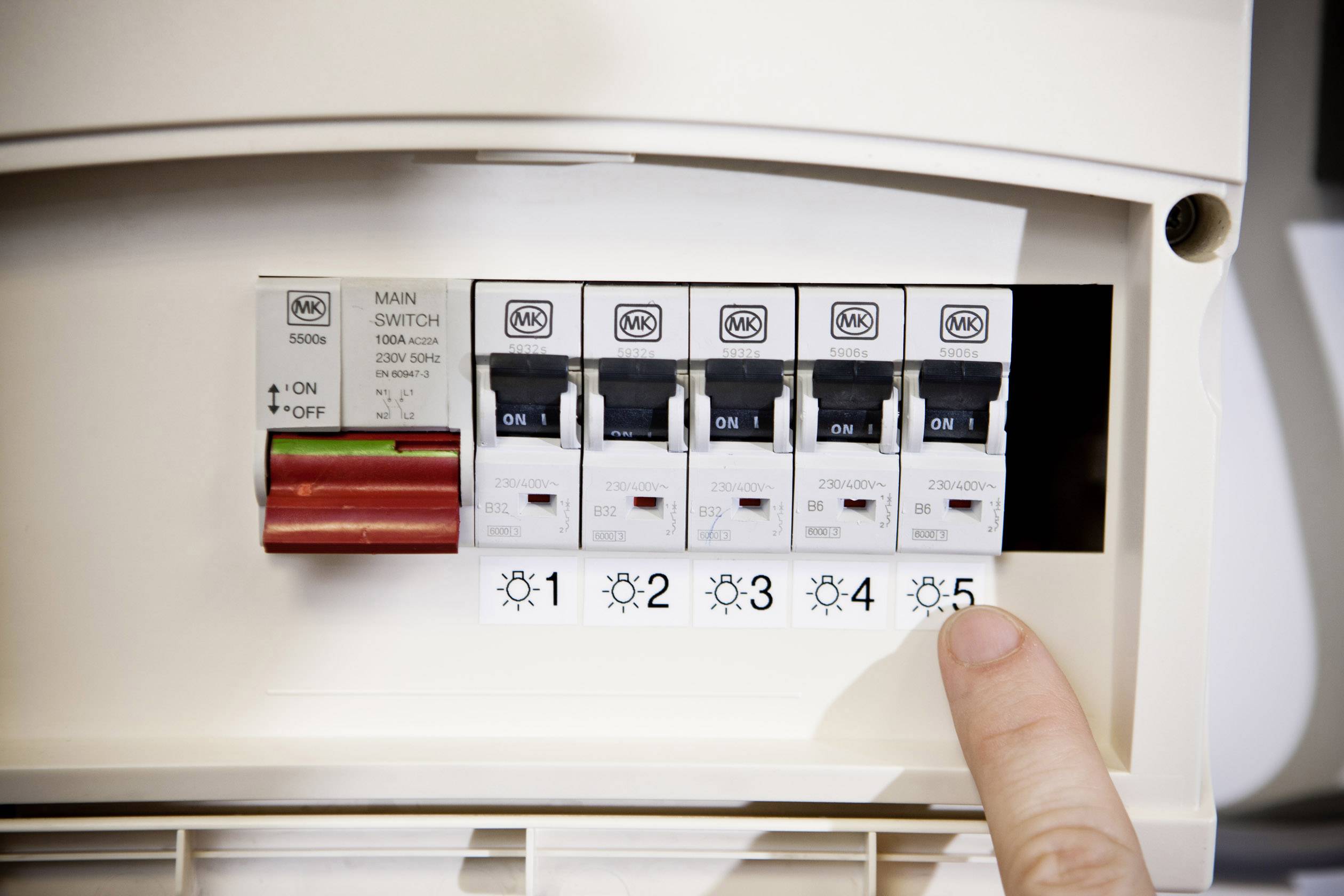 Un dito punta su un quadro elettrico con diversi interruttori numerati da 1 a 5. L'interruttore principale è spento.