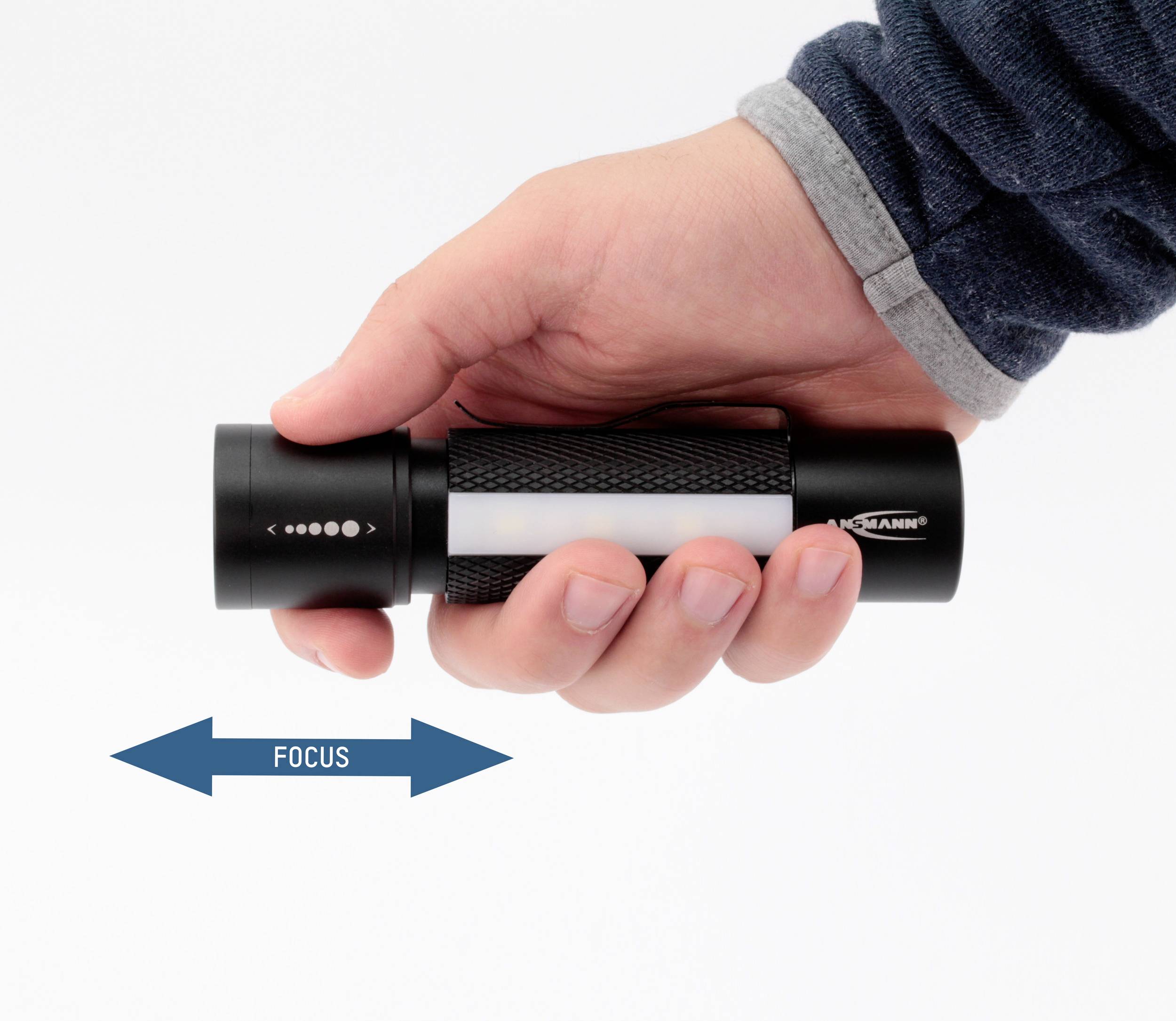 Una mano tiene una torcia. Una freccia doppia blu sotto indica la direzione di messa a fuoco della lampada, con la parola 'FOCUS'.