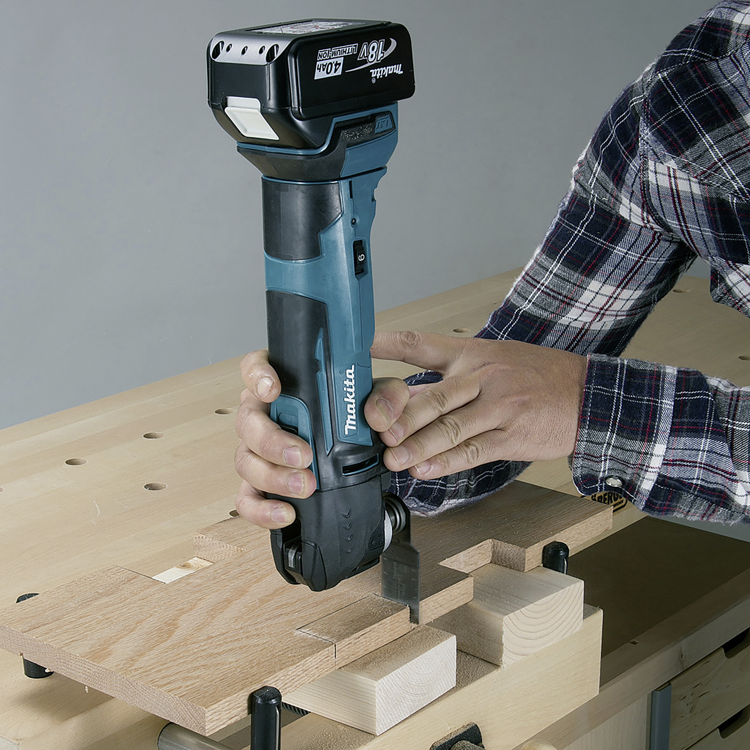 Una persona sta lavorando con un utensile elettrico blu su una superficie in legno per tagliare pezzi di legno con precisione.