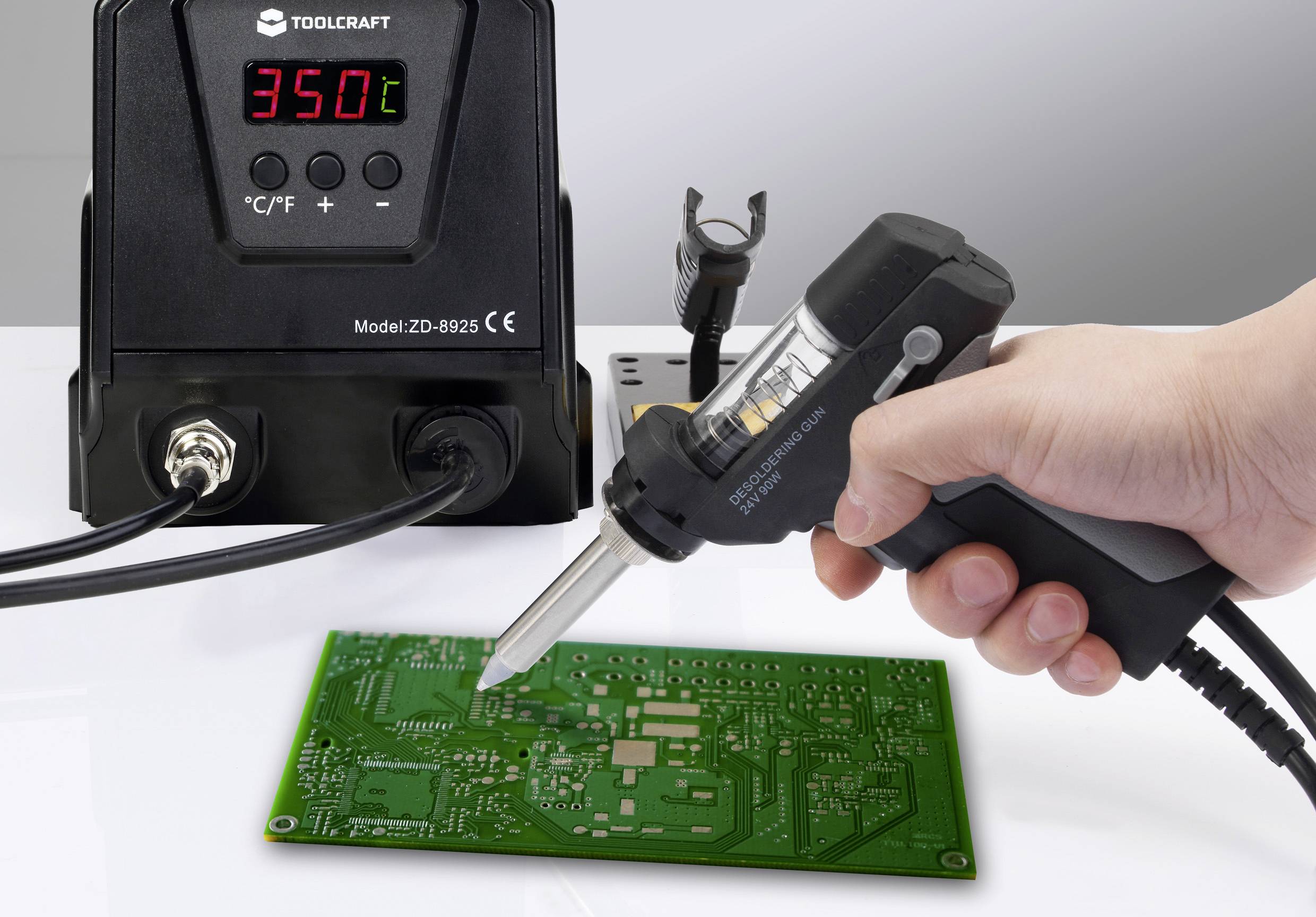 «Una mano utilizza un saldatore collegato a uno strumento che mostra '350°C' mentre lavora su una scheda elettronica verde, suggerendo una riparazione elettronica.»