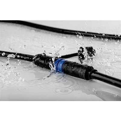 Un connettore elettrico a tenuta stagna spruzza acqua su una superficie liscia. I cavi sono collegati e visibili in primo piano.