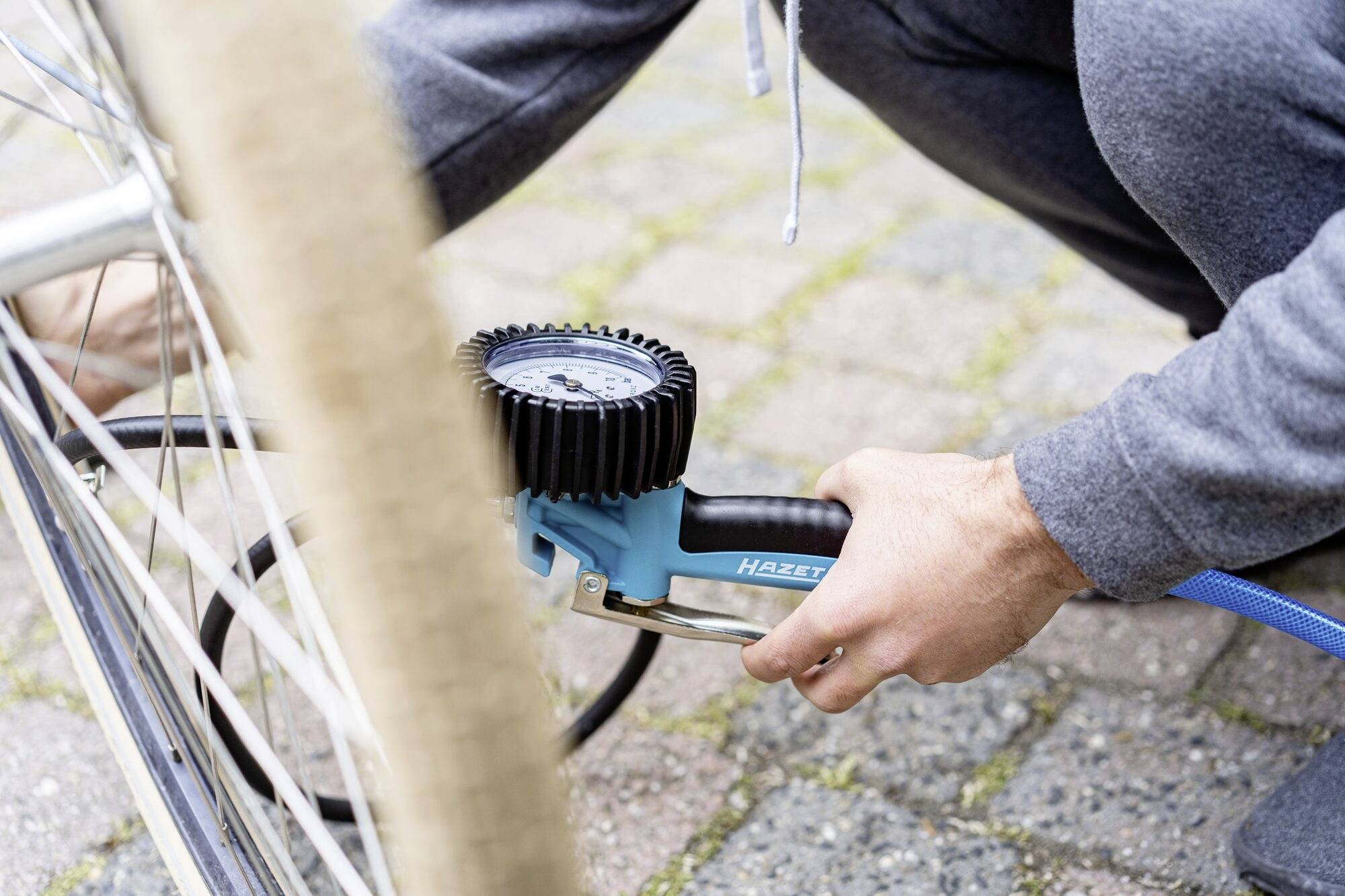 Una persona sta gonfiando un pneumatico di bicicletta con una pompa. L'attenzione è concentrata sull'azione di gonfiare la ruota.