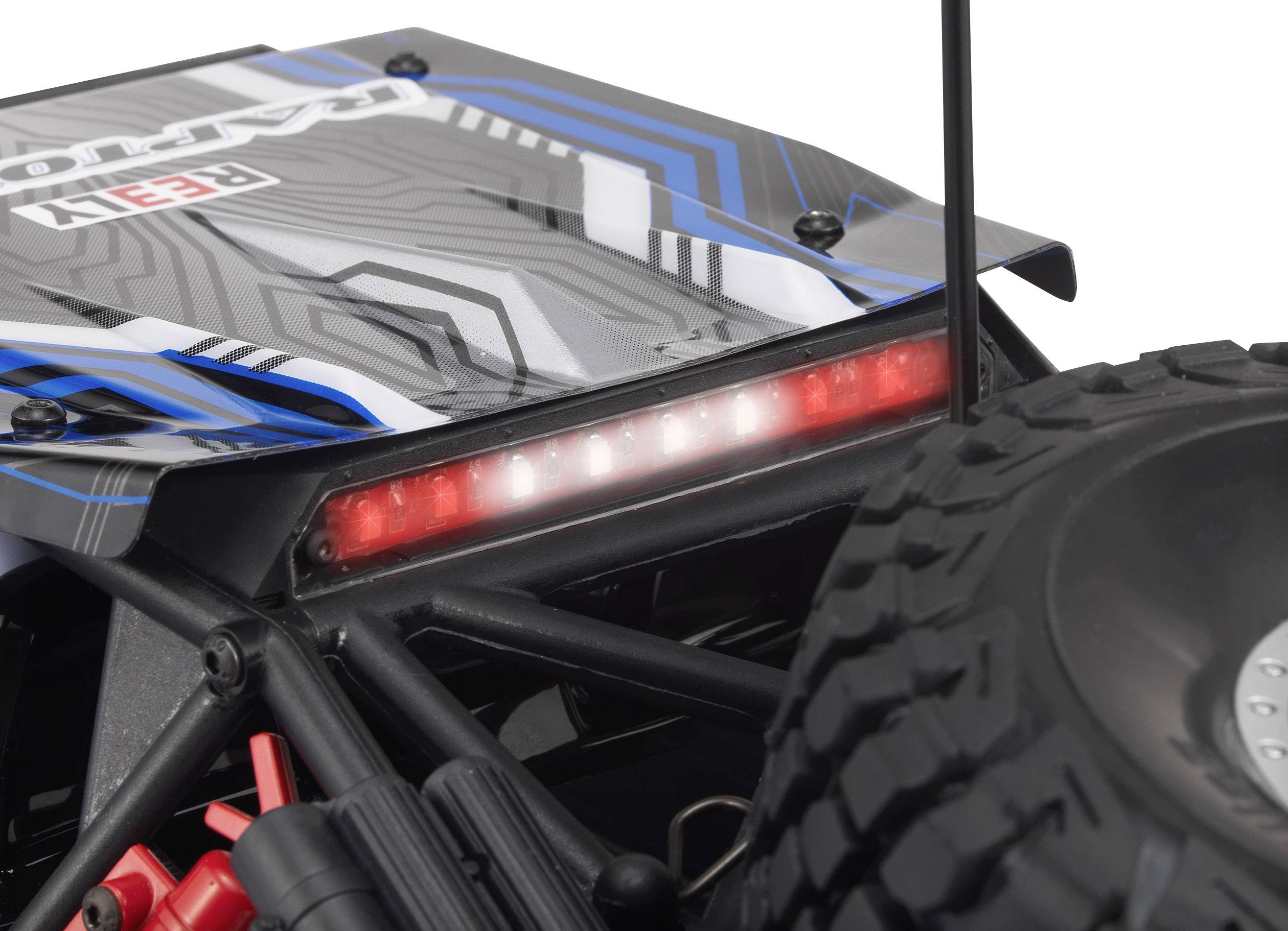Primo piano di un'auto radiocomandata con pneumatici tassellati e una striscia LED rossa illuminata sul retro.
