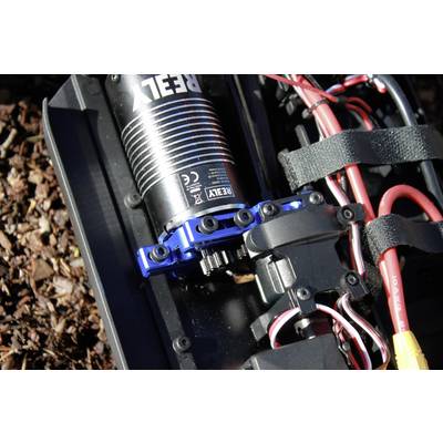 Motore elettrico di un'auto radiocomandata su un sentiero nel bosco, con cavi e supporti visibili.