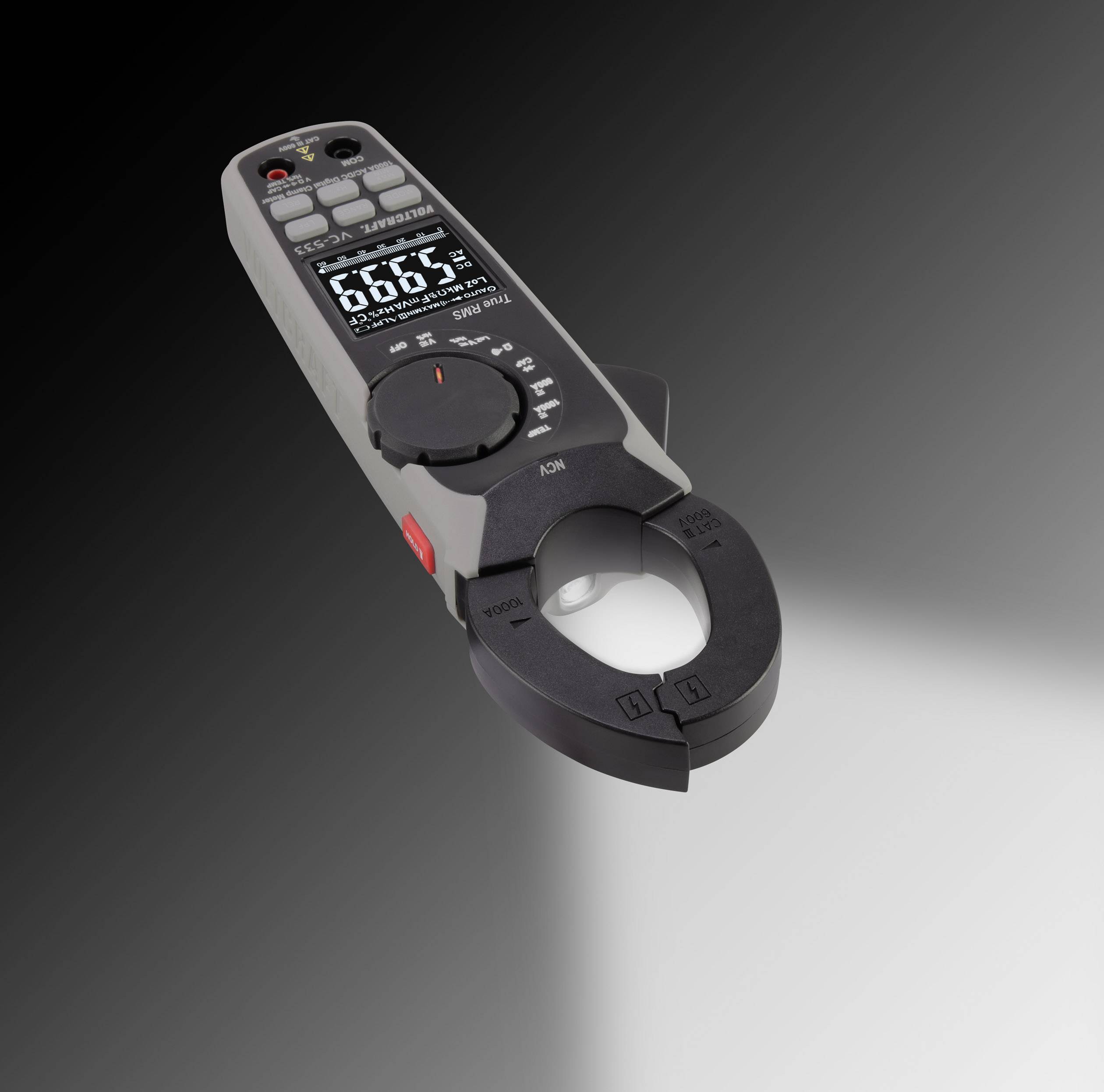 Dispositivo digitale per la misurazione dell'energia elettrica con sensore a pinza, posizionato su sfondo grigio, che mostra i valori di misurazione su un display illuminato.