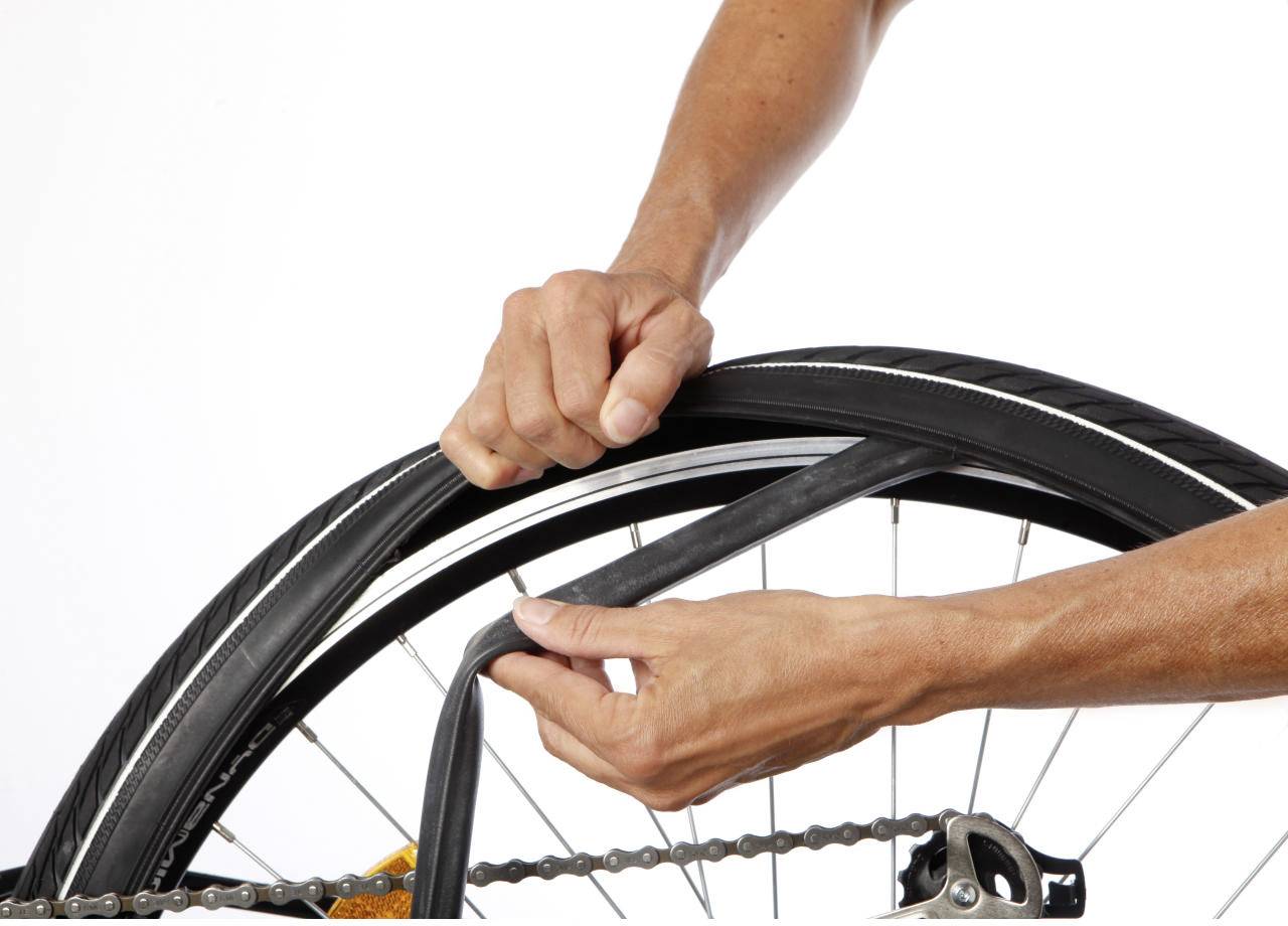 Una persona sta cambiando una camera d'aria della bicicletta. Le mani tengono la ruota e una nuova camera d'aria, mentre quella vecchia rimane sul telaio.