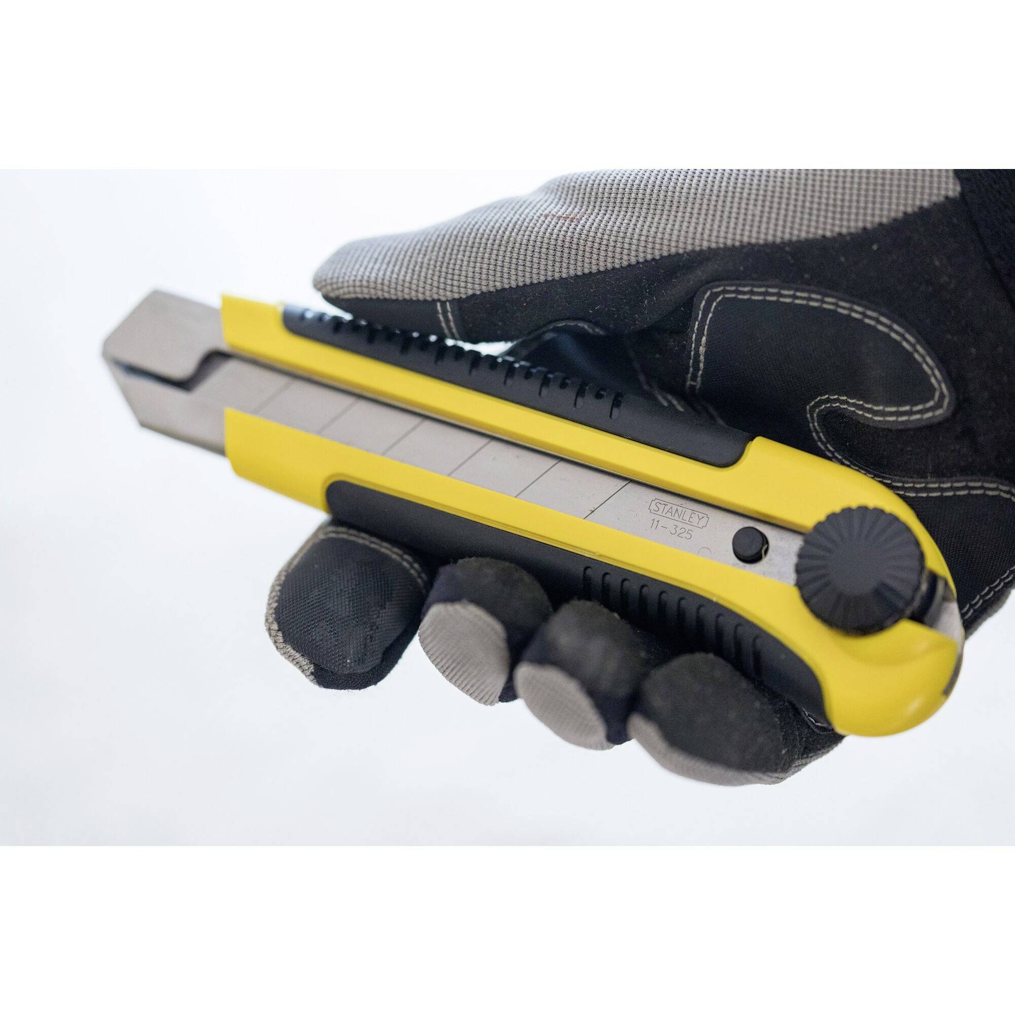 Una mano guantata tiene un coltello universale giallo e grigio con lama retrattile.