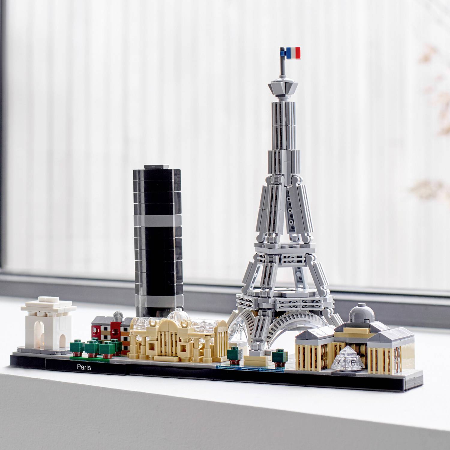 Un'installazione Lego con monumenti parigini: Arco di Trionfo, Torre Montparnasse, Torre Eiffel e Louvre con una piccola bandiera francese.