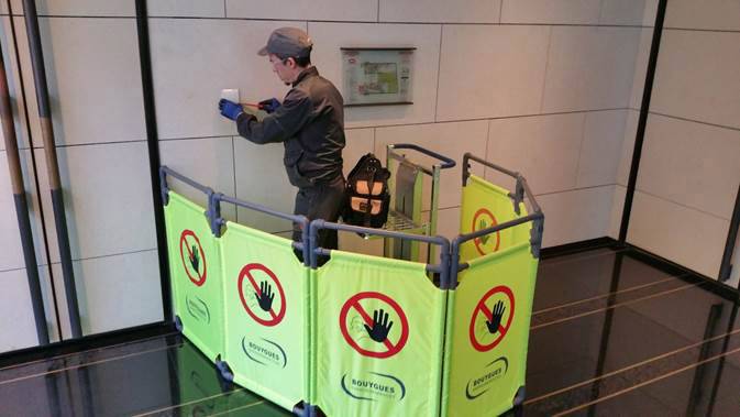 Un artigiano lavora in un'area recintata con cartelli di avvertimento 'Vietato l'accesso'.