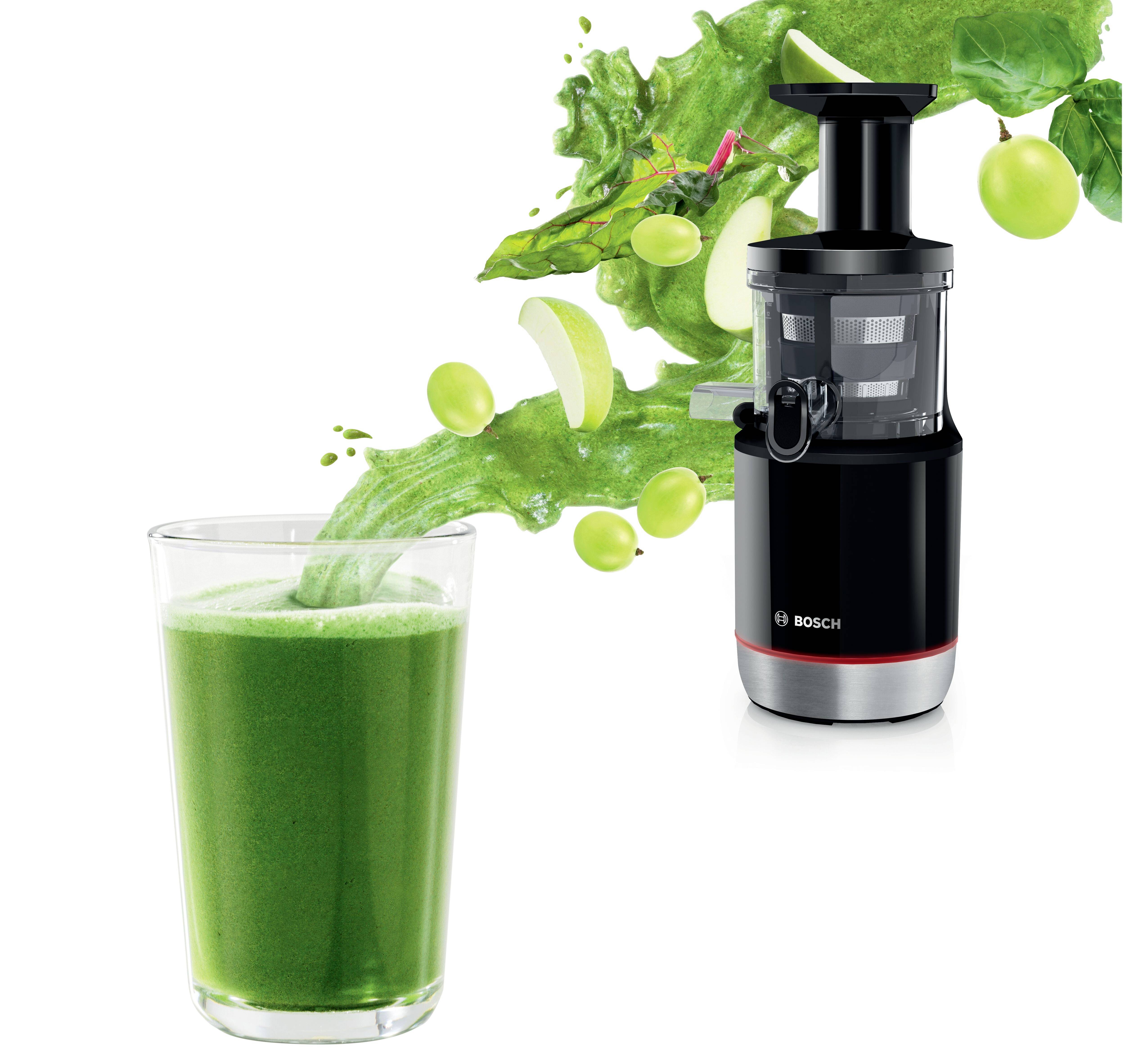 Estrattore Bosch con bicchiere di succo verde. Mele verdi e verdure sembrano trasferirsi dall'estrattore al bicchiere.