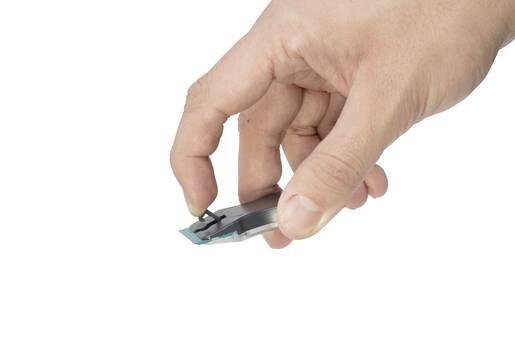 Una mano tiene un'unità USB tra pollice e indice. La chiavetta è nera con un'estremità blu.