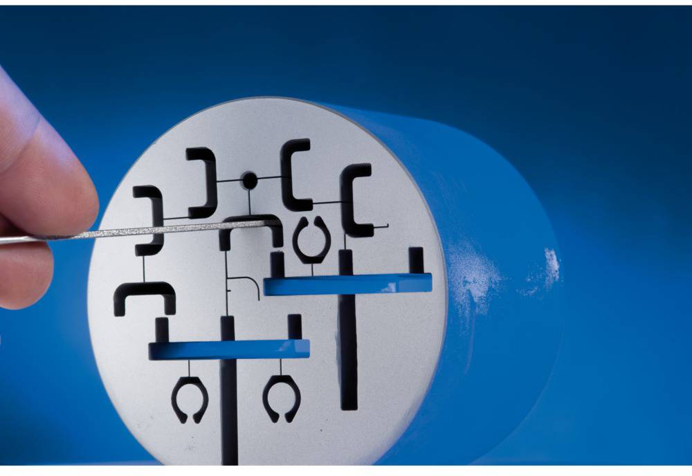 Una mano tiene un sottile ago metallico che viene inserito in un modello di serratura che mostra i meccanismi di una funzione di blocco.