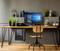 Scrivania moderna con monitor che mostra Windows 10. Piante e decorazioni sullo scaffale, sedia in legno davanti.