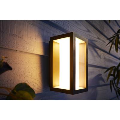 Applique da esterno su una facciata in legno che emana una luce calda, creando un'atmosfera serale accogliente.