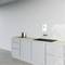 Un angolo cucina minimalista con armadi grigi, un piano di lavoro in legno, una cucina elettrica, un bollitore e una parete bianca.