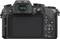 Vista posteriore di una fotocamera mirrorless con schermo LCD aperto e comandi come menu, ISO, impostazioni di messa a fuoco e mirino.