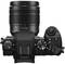Fotocamera digitale con un obiettivo fisso che mostra una lunghezza focale di 12-60 mm. Vista della fotocamera dall'alto con comandi visibili.