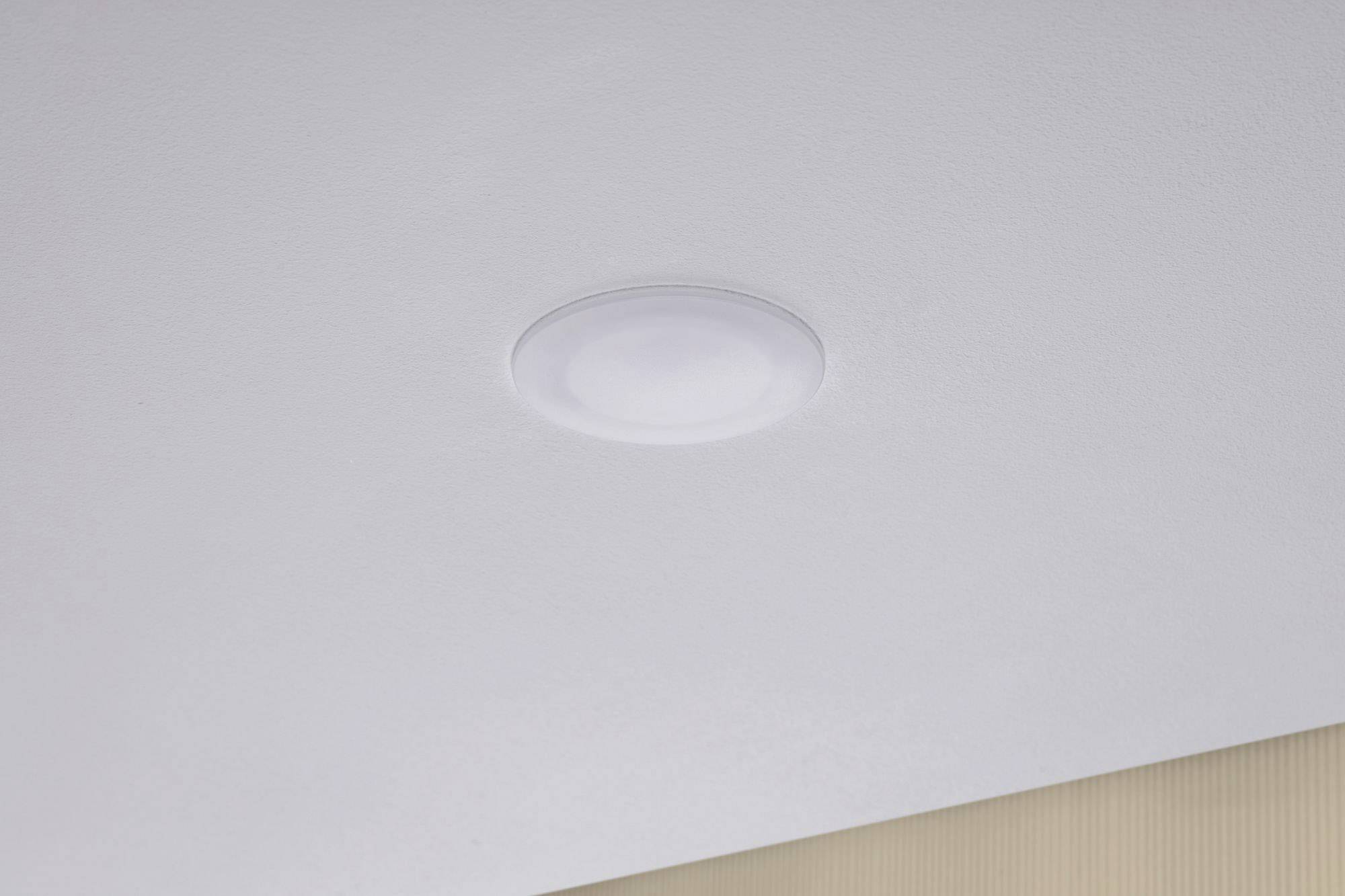 Una plafoniera rotonda incassata nel soffitto bianco di una stanza. La lampada è spenta.