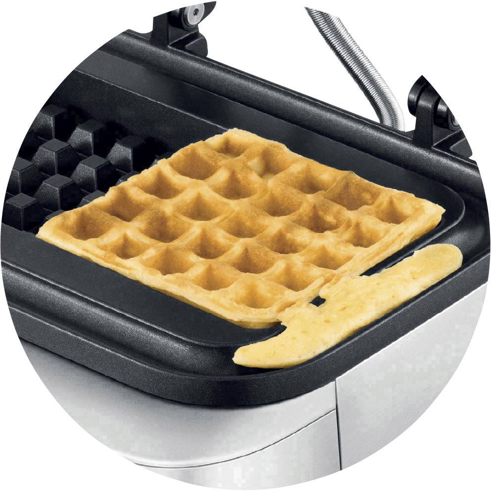 Un ferro per waffle con una cialde quadrata appena sfornata. Un piccolo quantitativo di impasto è colato accanto.