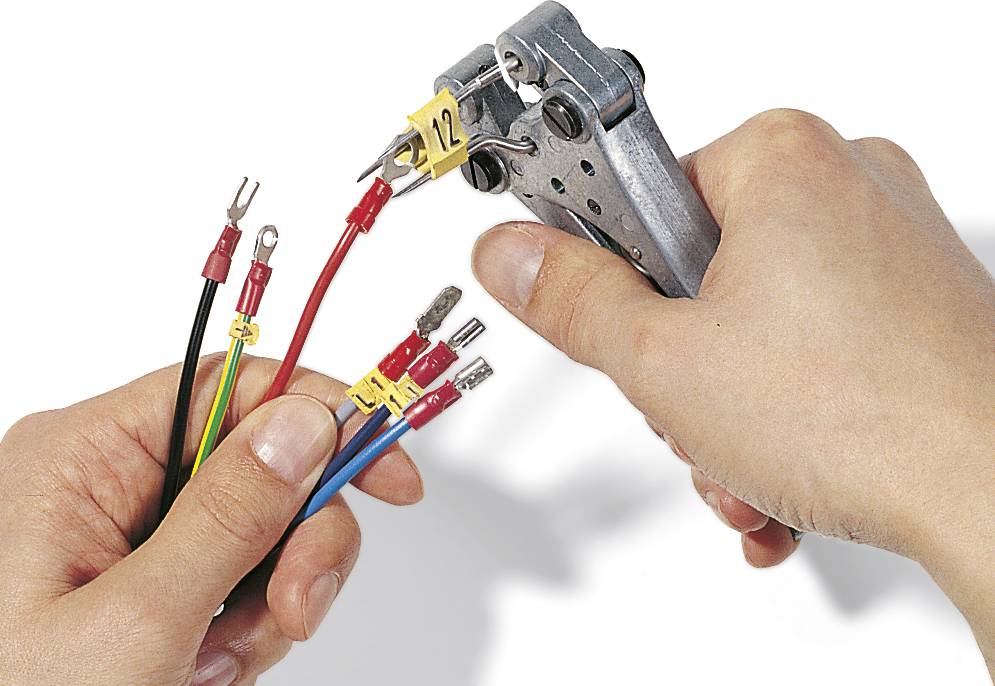 Una mano utilizza un utensile per fissare capicorda a quattro cavi di colori diversi. L'utensile è contrassegnato con il numero '12'.