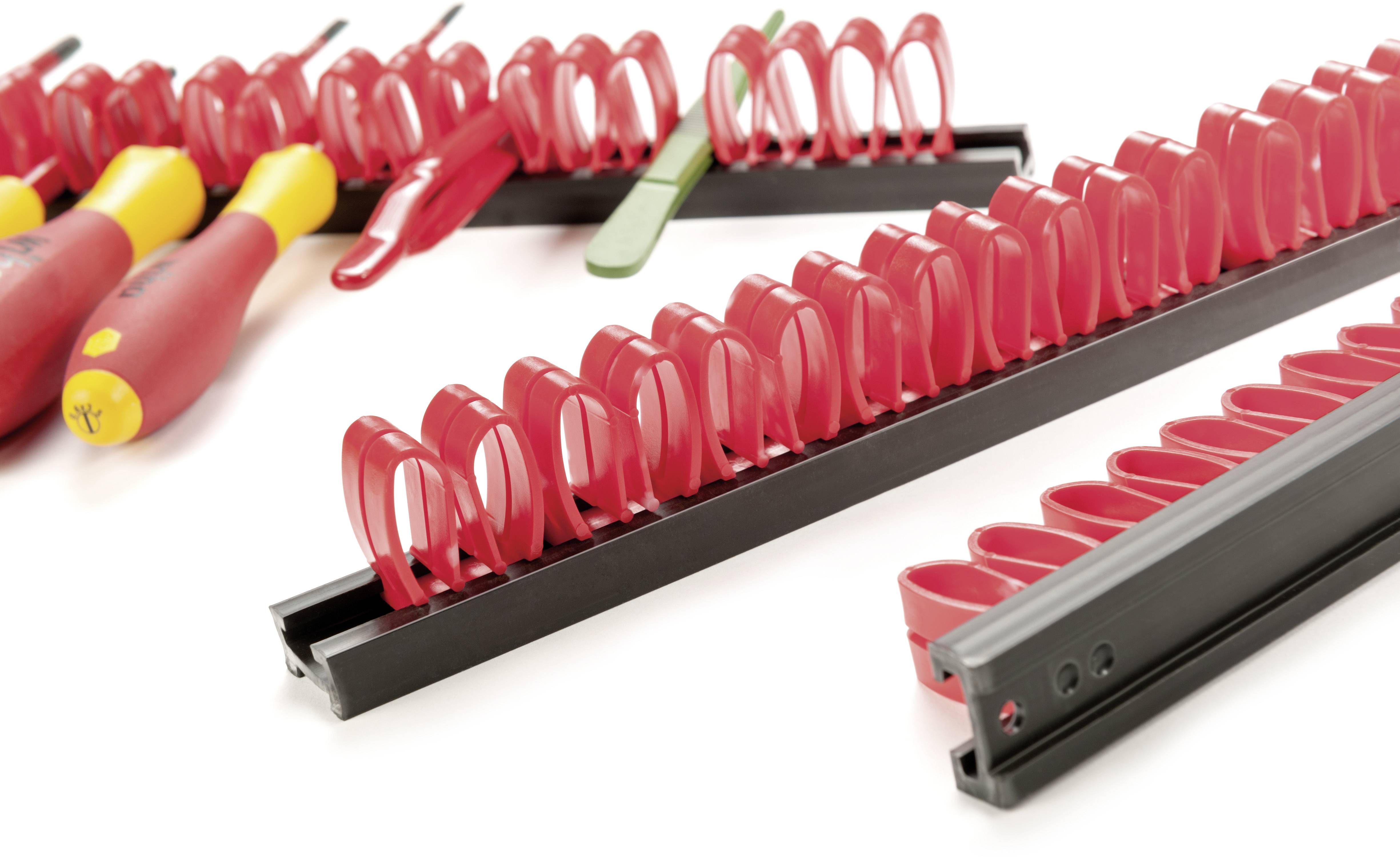 Diversi supporti rossi in plastica su guide nere che organizzano e tengono in sicurezza utensili come cacciaviti.