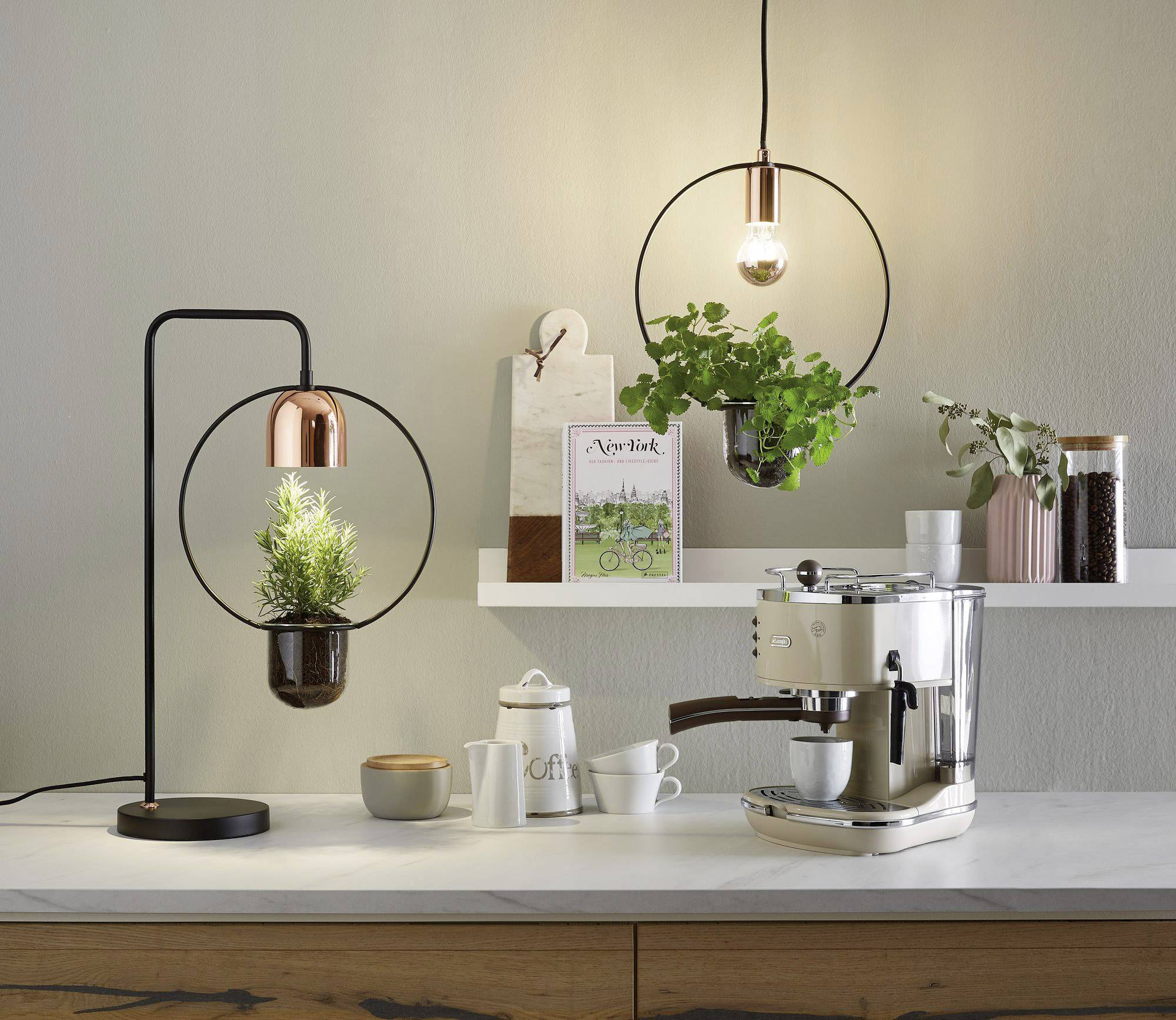 Cucina moderna con eleganza; macchina per espresso a destra, vaso di erbe e lampada a sinistra; estetica minimalista e illuminazione accogliente.