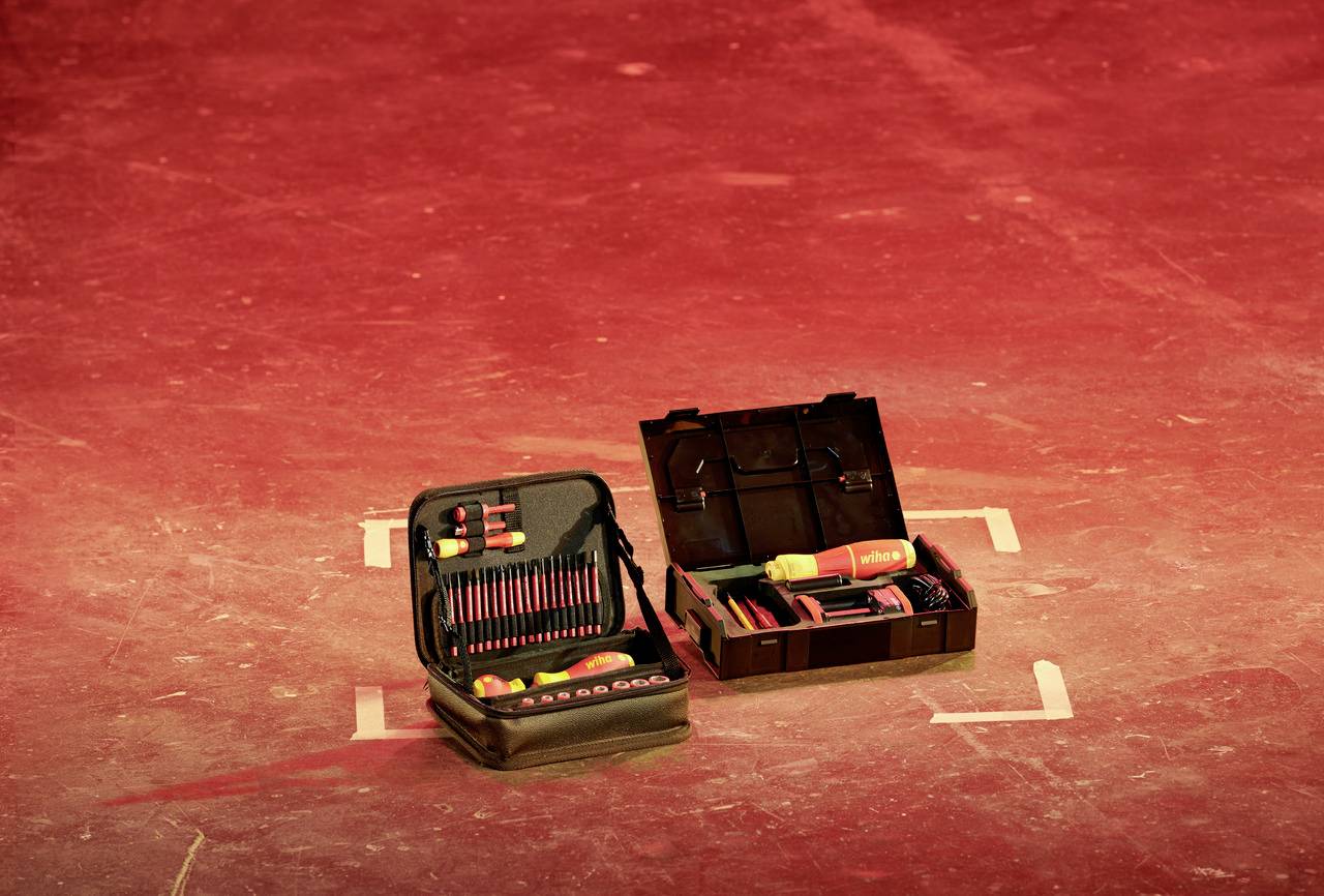 Due cassette degli attrezzi aperte con vari utensili poggiano su un pavimento illuminato di rosso.