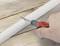 Una mano tiene un cacciavite su un tubo bianco sopra un tavolo di legno.