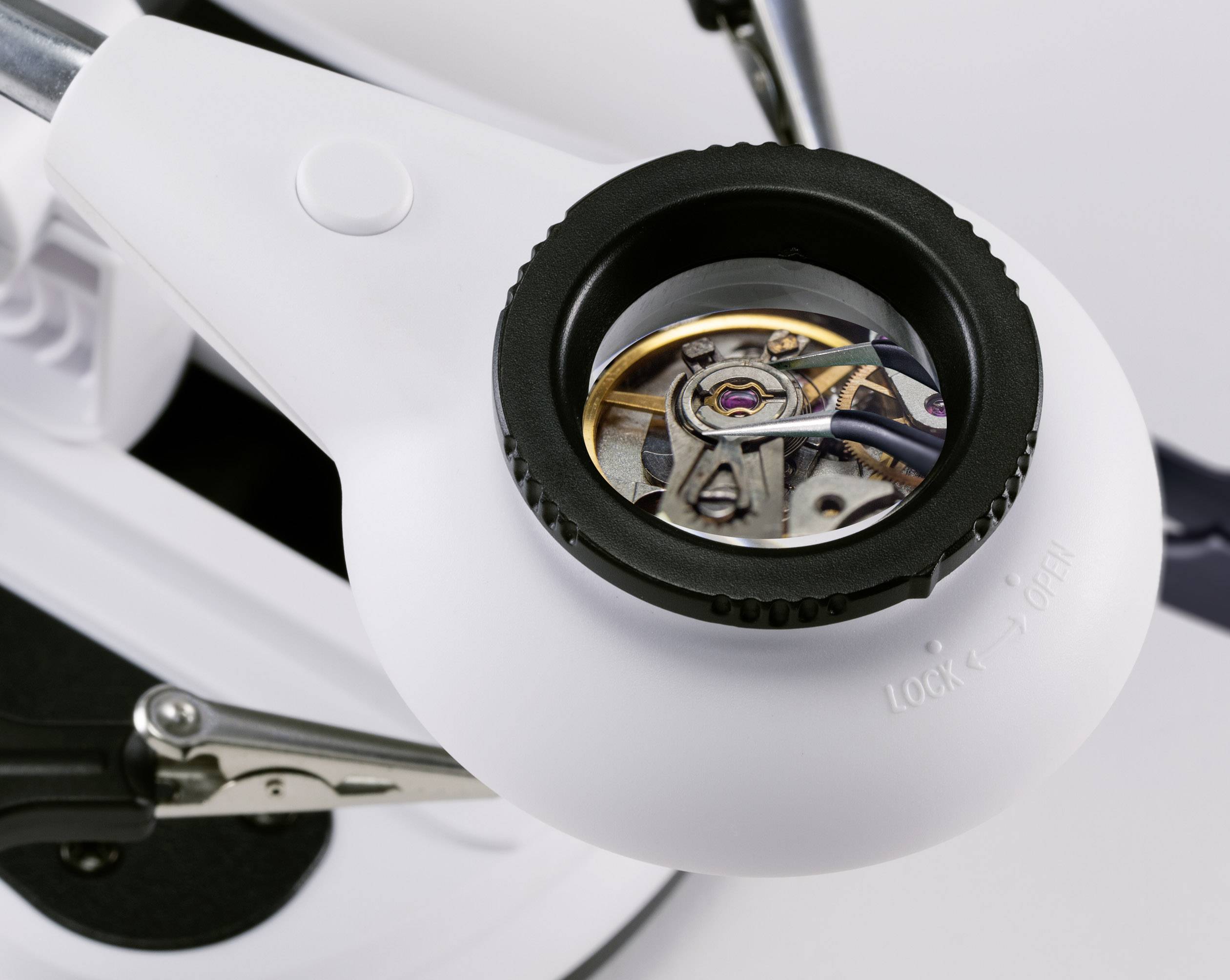 Una lente di ingrandimento da orologiaio ingrandisce il meccanismo dell'orologio, mostrando ingranaggi e meccanismi in primo piano.