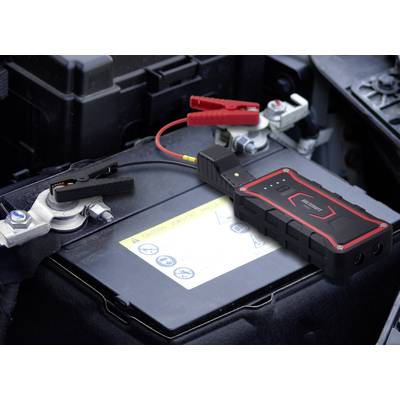 Una batteria dell'auto viene caricata da un dispositivo mobile di avviamento. I morsetti sono correttamente collegati ai poli della batteria.