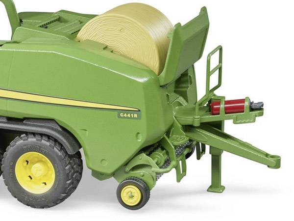 Una pressa agricola verde che comprime un pagliaio color marrone chiaro, mostrata su una superficie piana.