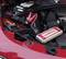 Una batteria dell'auto nel vano motore viene collegata con un avviatore d'emergenza portatile. I cavi rosso e nero sono collegati.