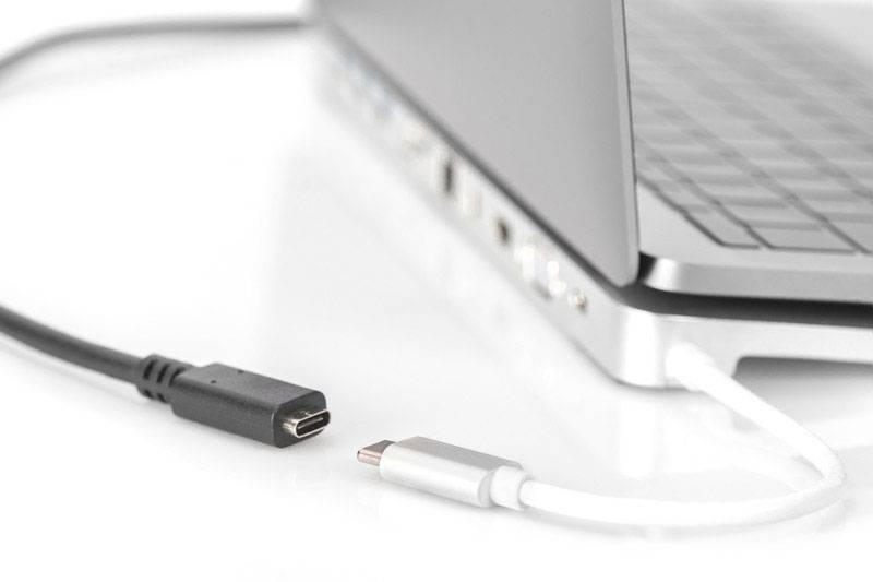 Un connettore USB-C è tenuto accanto a una porta USB-C aperta di un laptop, pronto per essere inserito. Il laptop è di colore argento.