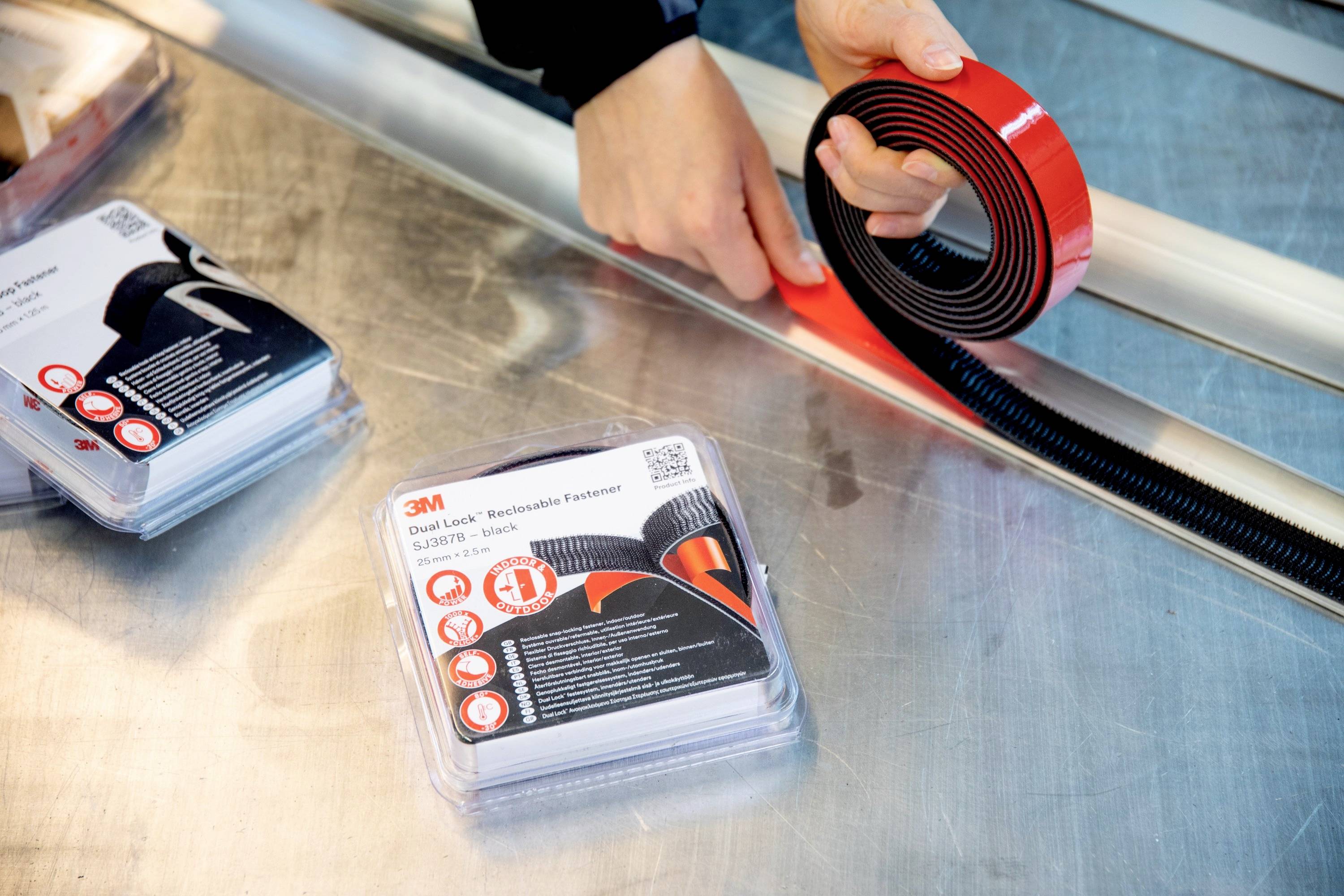 Una persona tiene un rotolo di nastro biadesivo 3M, pronto all'uso. Confezione con istruzioni e simboli accanto.