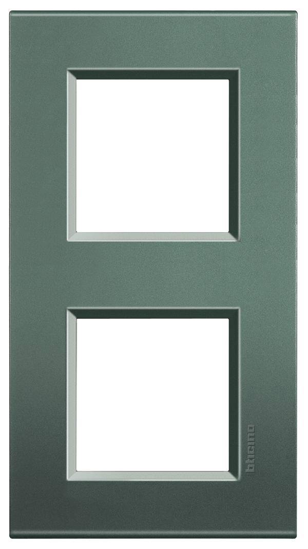 Cornice doppia in metallo con tagli rettangolari, idonea per l'alloggiamento di due inserti interruttori, in colore verde scuro.