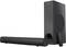 Soundbar e subwoofer in nero. Il subwoofer è in posizione verticale, la soundbar orizzontale. Un telecomando è poggiato accanto.