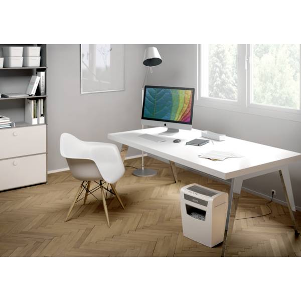 Un ufficio moderno con scrivania, monitor, lampada, sedia da ufficio e distruggidocumenti su pavimento in legno. Libreria sullo sfondo.
