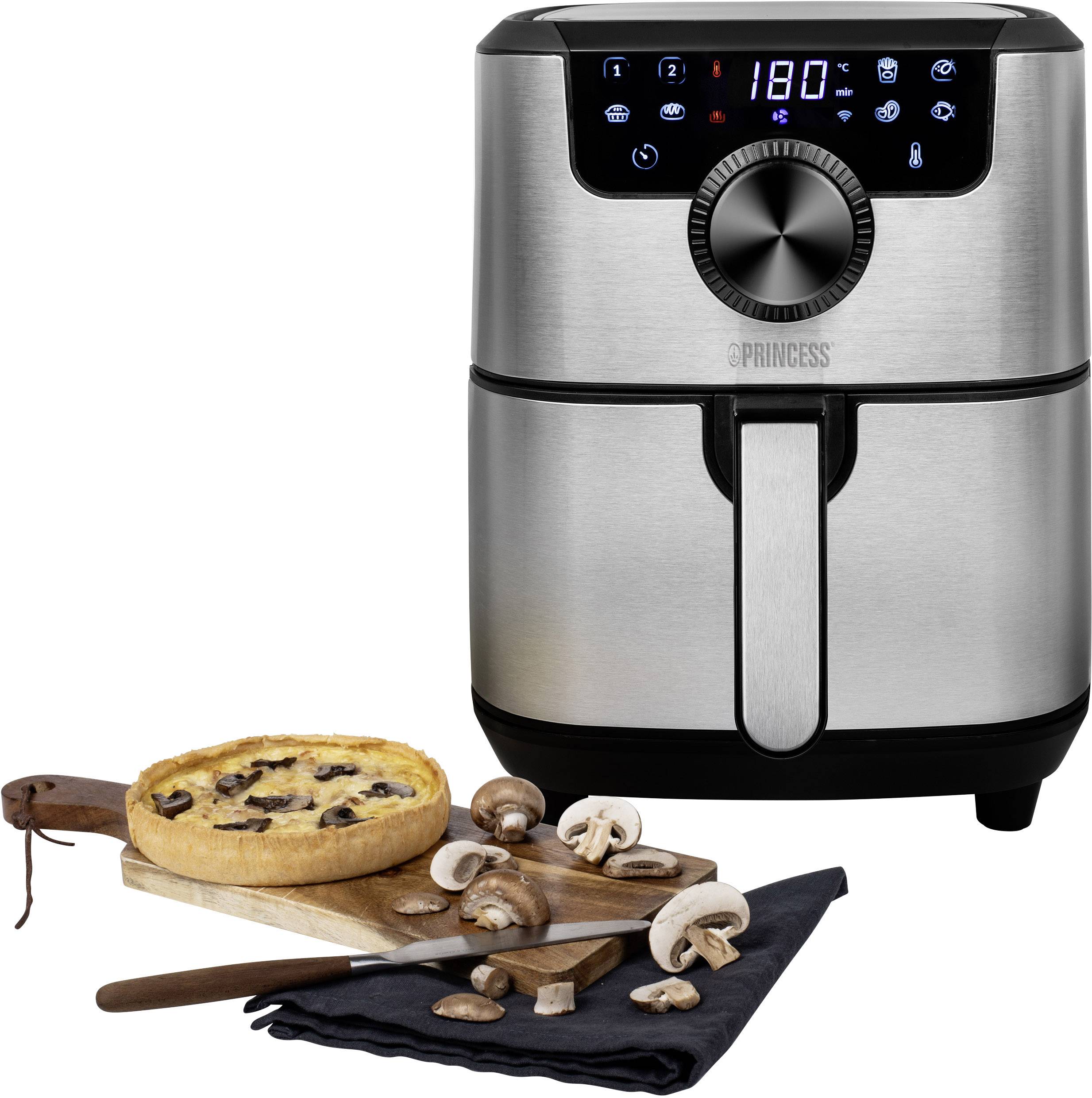 Friggitrice ad aria calda in acciaio inossidabile con display digitale che mostra 180 gradi. Accanto un tagliere di legno con un piatto di funghi al forno e funghi freschi.