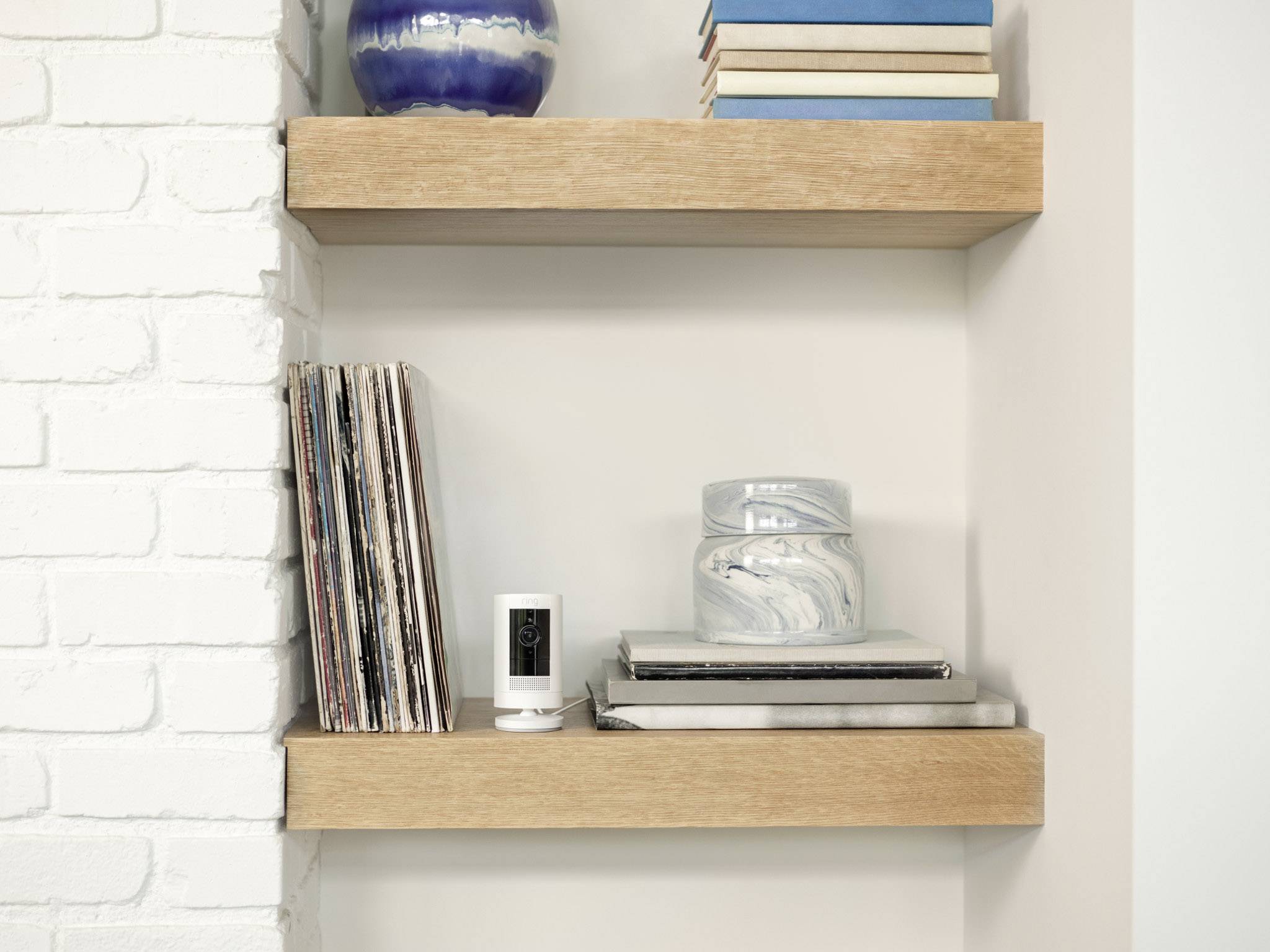 Uno scaffale con diversi dischi in vinile, una piccola macchina fotografica e libri. Bicchieri decorativi sono posizionati sui libri impilati accanto.