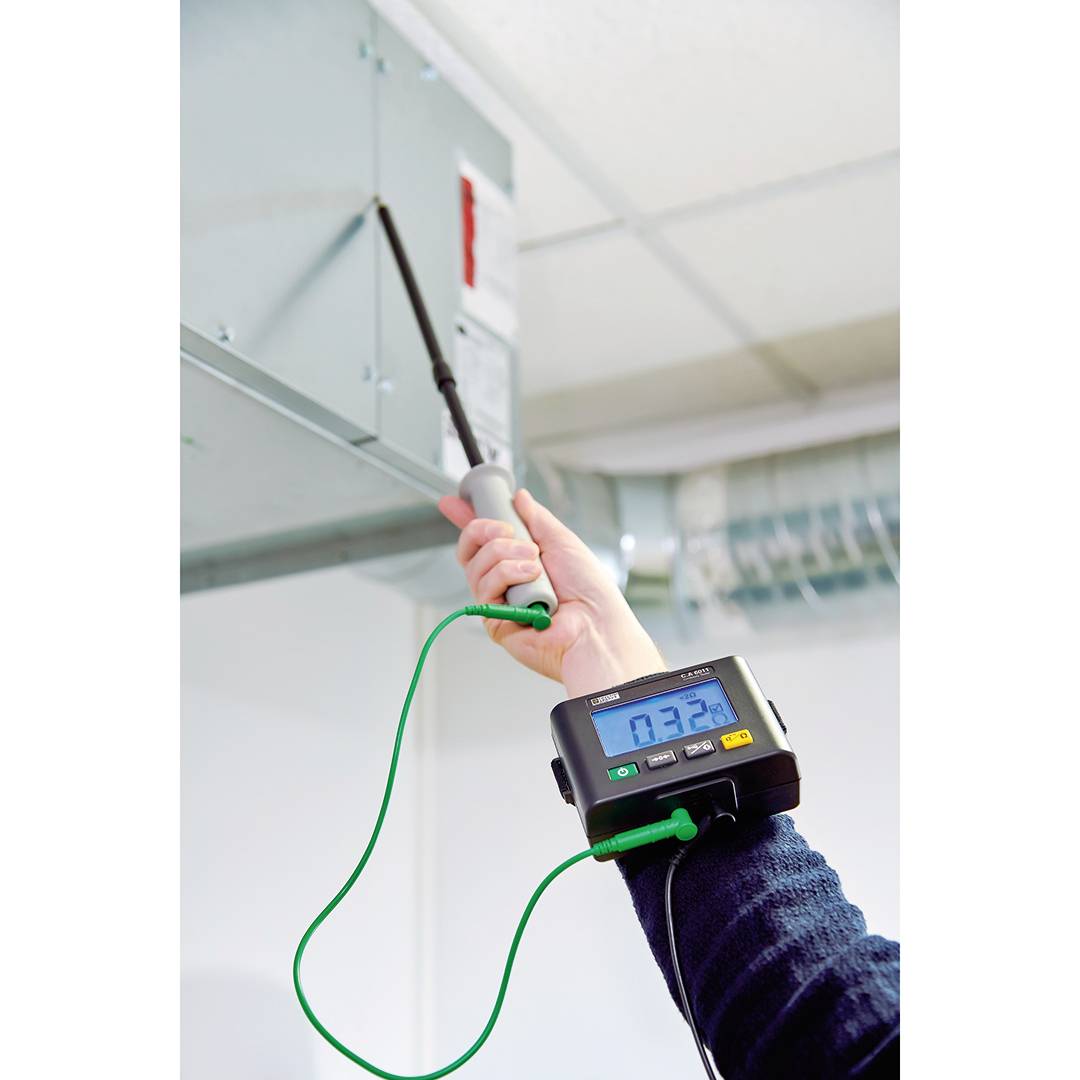 Una persona sta controllando un impianto di ventilazione con un dispositivo elettronico collegato tramite un cavo verde.