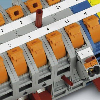 Morsetti elettrici multipolari con attacchi numerati, parzialmente arancioni, montati su una guida di supporto.