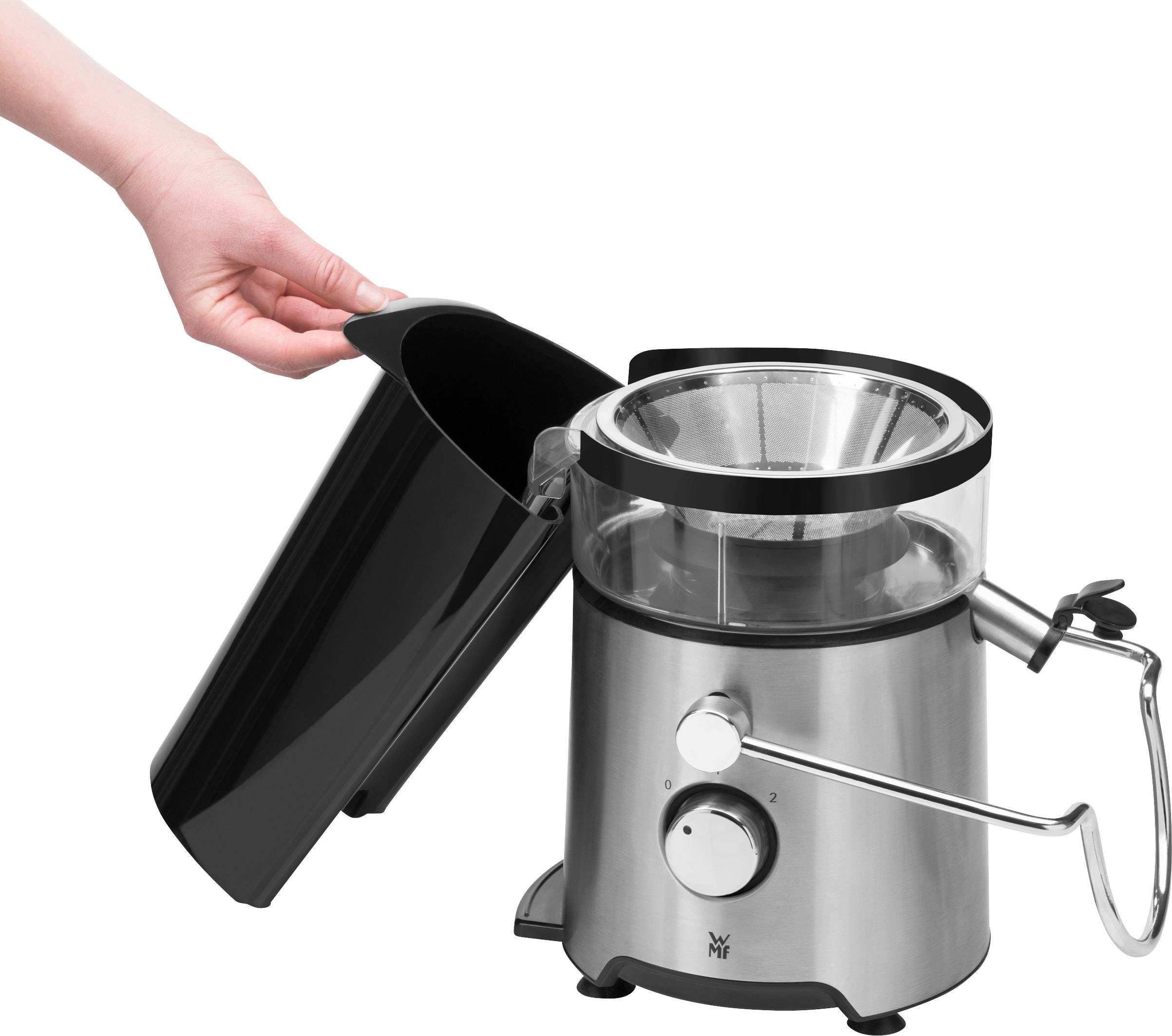 Mano che rimuove un coperchio nero da un estrattore di succo argentato. L'estrattore di succo ha una leva e una manopola di regolazione sul davanti.