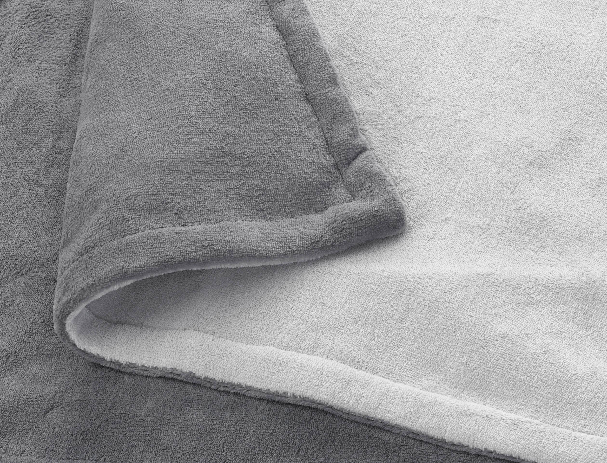 Coperta grigia, morbida e pieghettata, mostra la struttura e lo spessore del materiale.