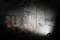 Operai edili all'interno di un edificio mentre eseguono lavori di muratura e pitturazione. Ponteggi sullo sfondo, con attrezzi e materiali disponibili.