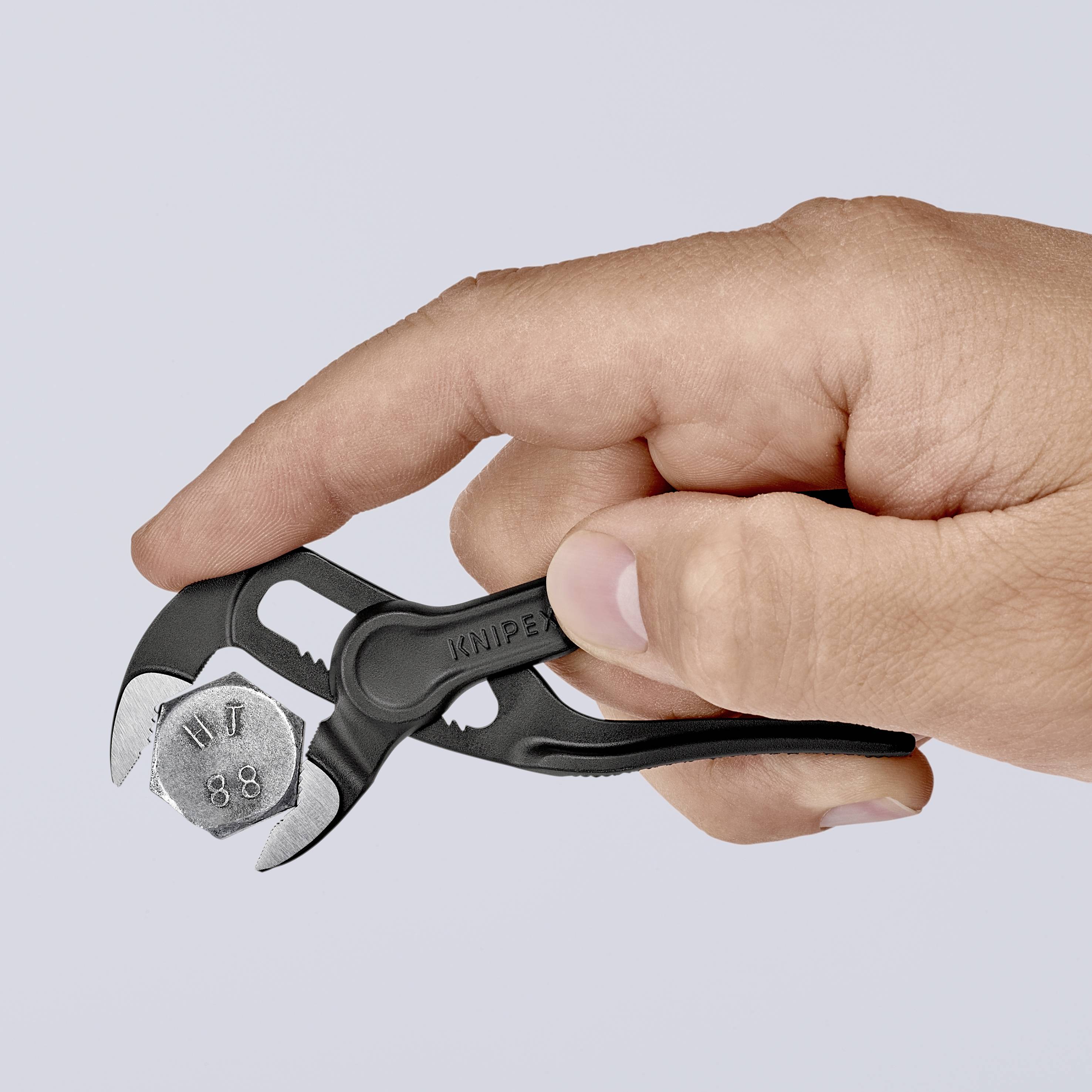 Una mano tiene una piccola pinza per pompa idraulica nera. La pinza è aperta e mostra la dentatura delle ganasce.