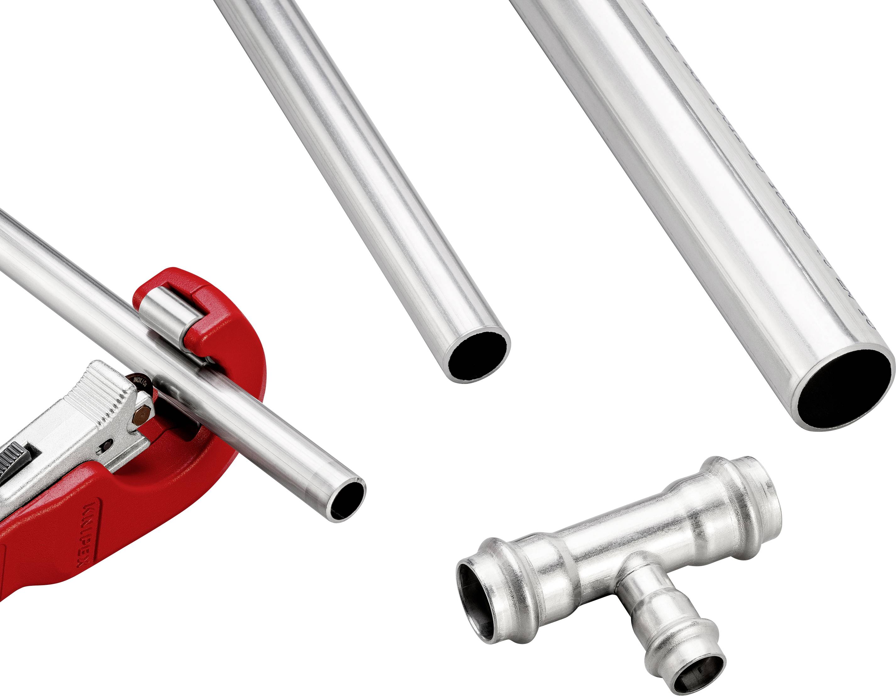 Tubi metallici e un raccordo a T sono posizionati uno accanto all'altro. Un tagliatubi taglia uno dei tubi. Utensili e materiali per l'installazione di tubazioni.