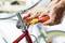 Una persona ripara una bicicletta rossa, utilizzando un cacciavite sul manubrio. Focus sugli attrezzi e sulle mani.